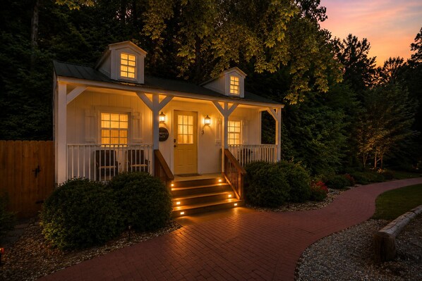 A two-story house with a porch, steps leading to the entrance, and a pathway leading to the door.