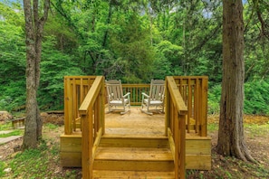 A wooden deck with two rocking chairs facing a forest.