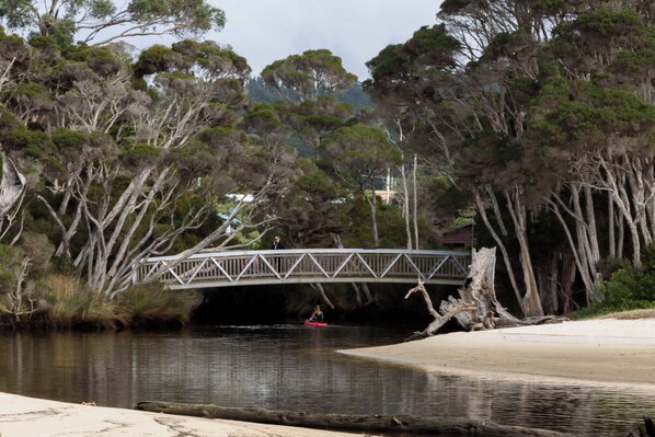 Un río con un puente de madera, un kayak y una playa de arena.
