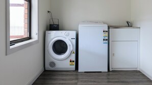 A laundry room with a washing machine, a dryer, and a sink. - Family Comfort in the Stunning Sisters Beach (Sisters Beach)