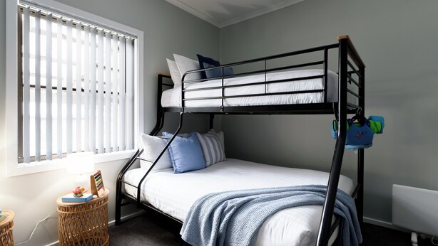 A bunk bed room with a window, a small round table, and a radiator. - Family Comfort in the Stunning Sisters Beach (Sisters Beach)
