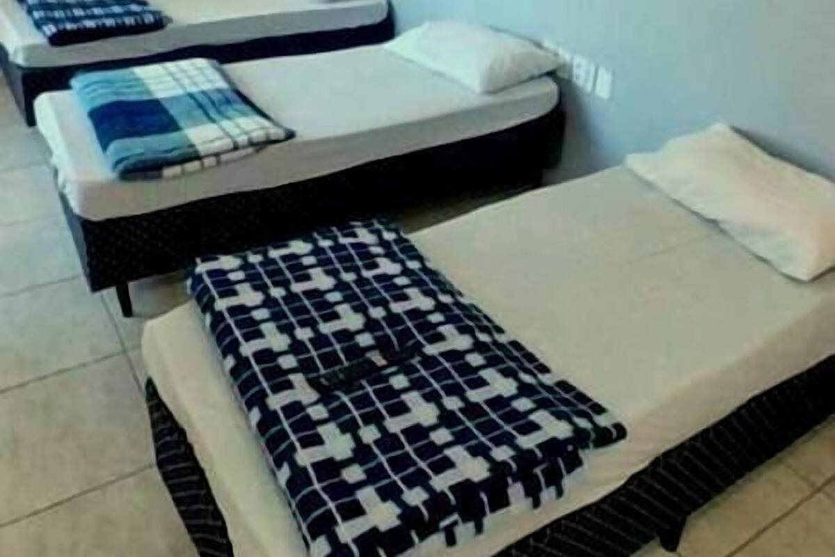 Una habitación con tres camas individuales, cada una con una colcha y almohadas estampadas.