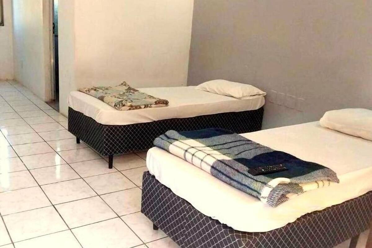 Dos camas individuales con ropa de cama estampada, suelo de baldosas y pared lisa.