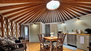 Un intérieur chaleureux avec une table et des chaises en bois, un canapé et un coin cuisine équipé de placards et d’appareils électroménagers.