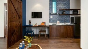 A modern kitchen with wooden cabinets, a blue backsplash, and a large wooden door.