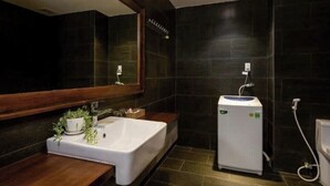 A modern bathroom with a large white bathtub, a small white sink, and a compact white heater.