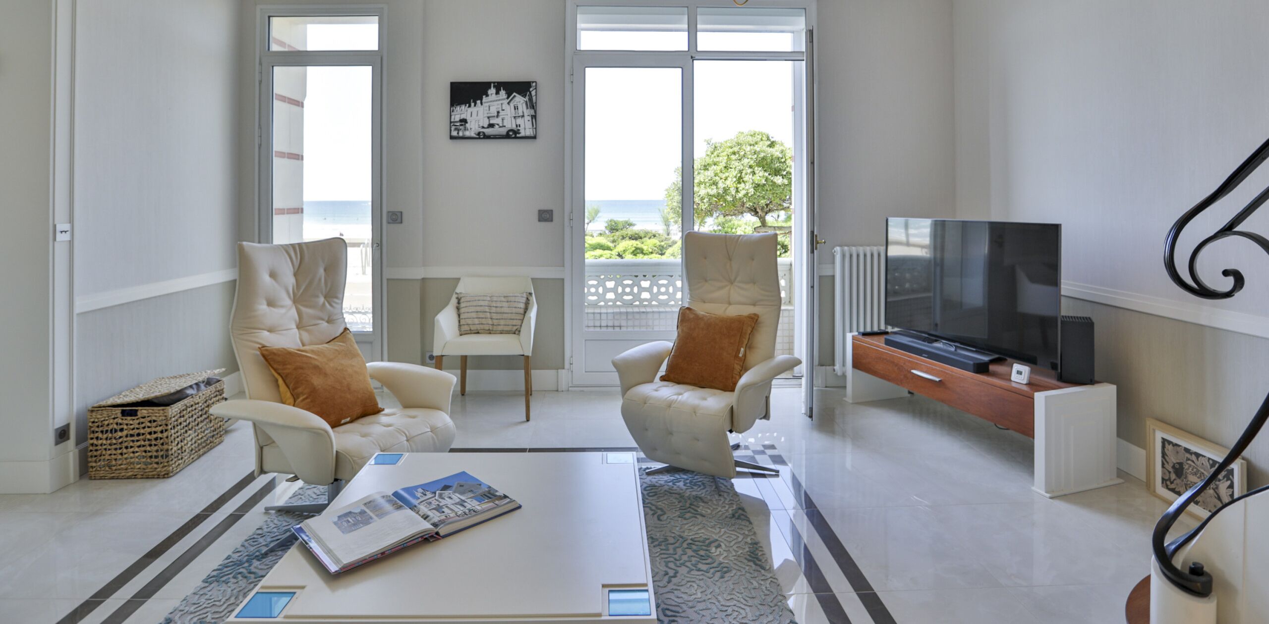 Un salon moderne comprenant un canapé, des fauteuils, une table basse et un téléviseur.