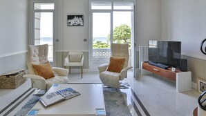 En moderne stue med sofa, lænestole, sofabord og fjernsyn.