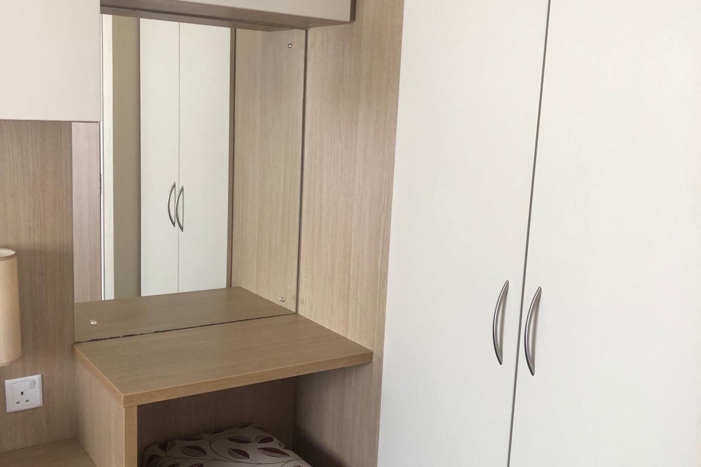 Une chambre à coucher avec une armoire en bois, un miroir et une table de chevet.