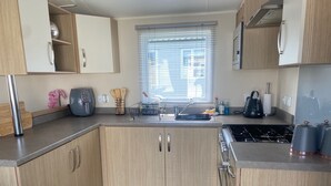 Une cuisine moderne avec des meubles en bois, un four encastré et une cuisinière à gaz.