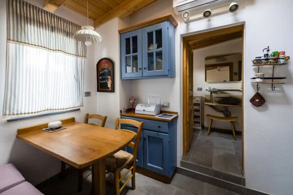 A kitchen with a wooden table, blue cabinets, and a window with curtains.