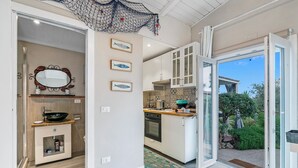 A modern kitchen with white cabinets, a large window, and a view of the garden.