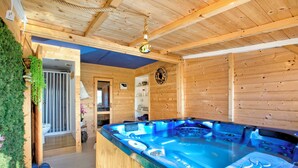 A wooden cabin with a hot tub, wooden walls, and a ceiling with exposed beams.