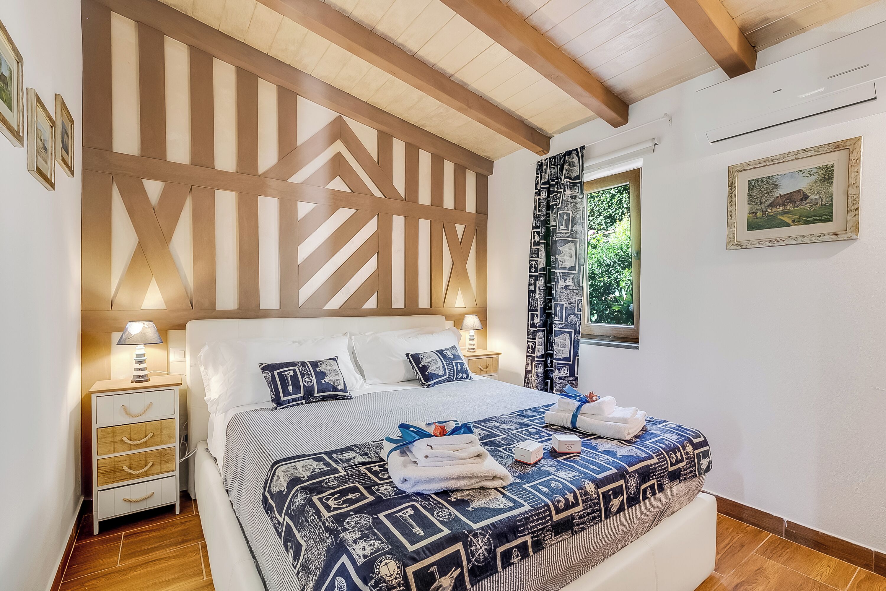 A neatly made bed with a patterned bedspread, a wooden headboard, and a nightstand with a lamp.