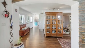 A spacious hallway with a wooden cabinet, a potted plant, and a bench.
