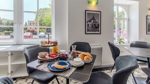 Un coin repas avec une table mise pour le petit-déjeuner, comprenant des assiettes, des bols et une carafe de jus de fruits.
