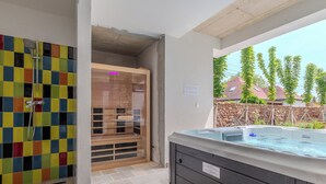Une salle de bain dotée d’une douche carrelée aux couleurs vives, d’un sauna en verre et d’un jacuzzi offrant une vue sur l’extérieur.