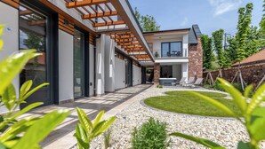 Une maison moderne dotée d’un patio, d’un mur en pierre et d’un jardin bien entretenu.