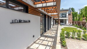 Un bâtiment moderne, doté d’une plaque signalétique, d’une allée couverte et d’un jardin aménagé.