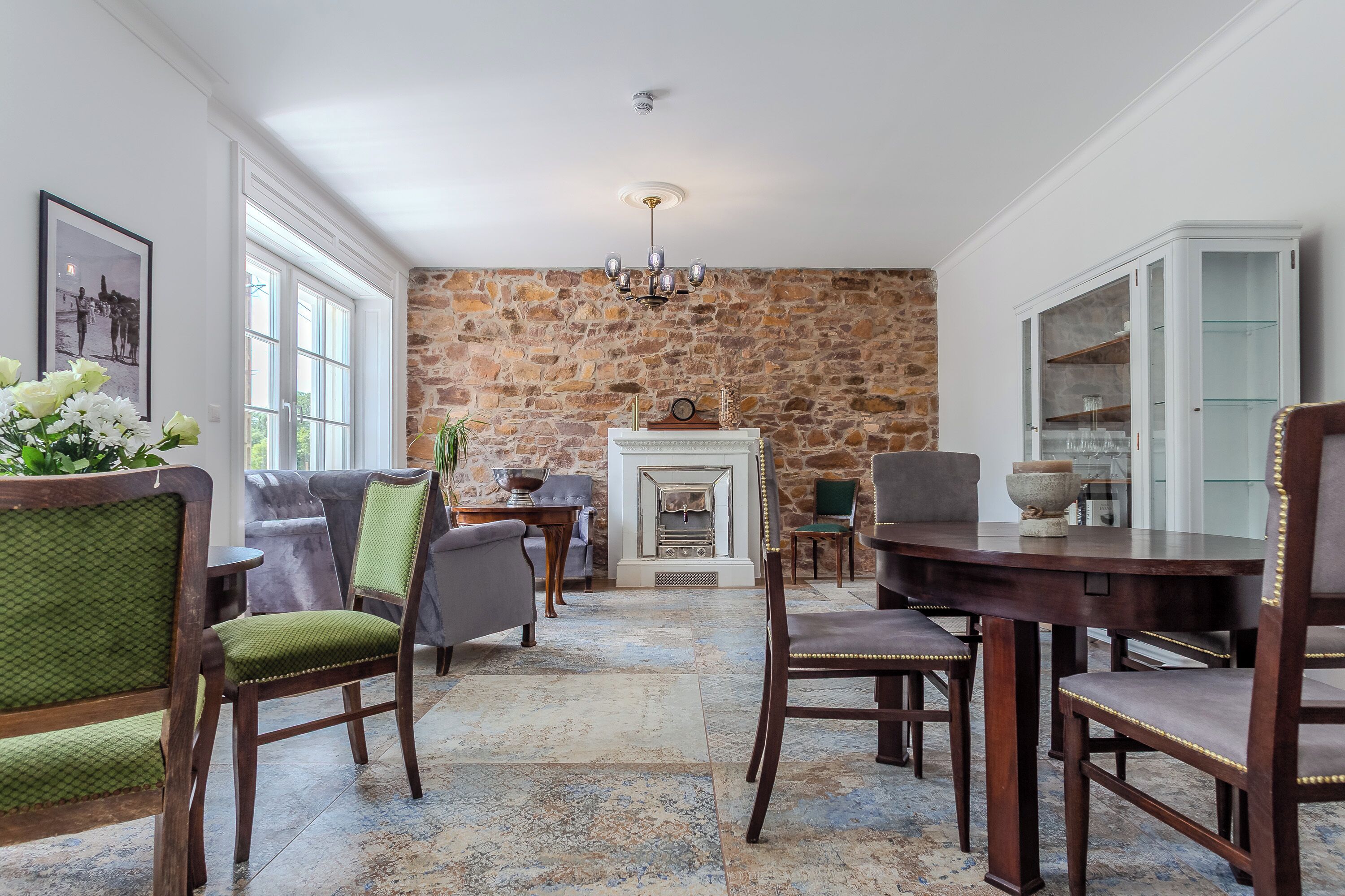 A dining area with a stone wall, a fireplace, and a chandelier.
