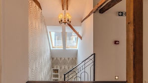 A staircase with a black metal railing, a chandelier, and a patterned wall. - Fulop Panzio-Goldenrod Room, Révfülöp, Hungary (Révfülöp)