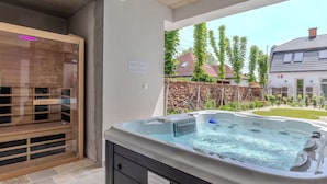 A hot tub with a stone wall and wooden deck in a backyard. - Fulop Panzio-Goldenrod Room, Révfülöp, Hungary (Révfülöp)