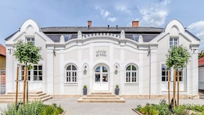 A white building with a central entrance, arched windows, and a sign above the door. - Fulop Panzio-Goldenrod Room, Révfülöp, Hungary (Révfülöp)