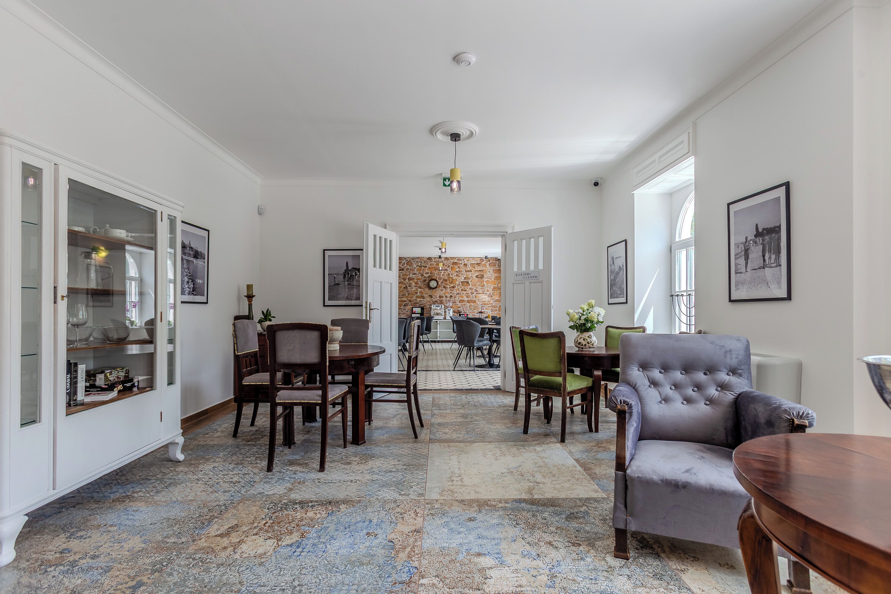 A spacious living area with a dining set, a grey armchair, and a coffee table.