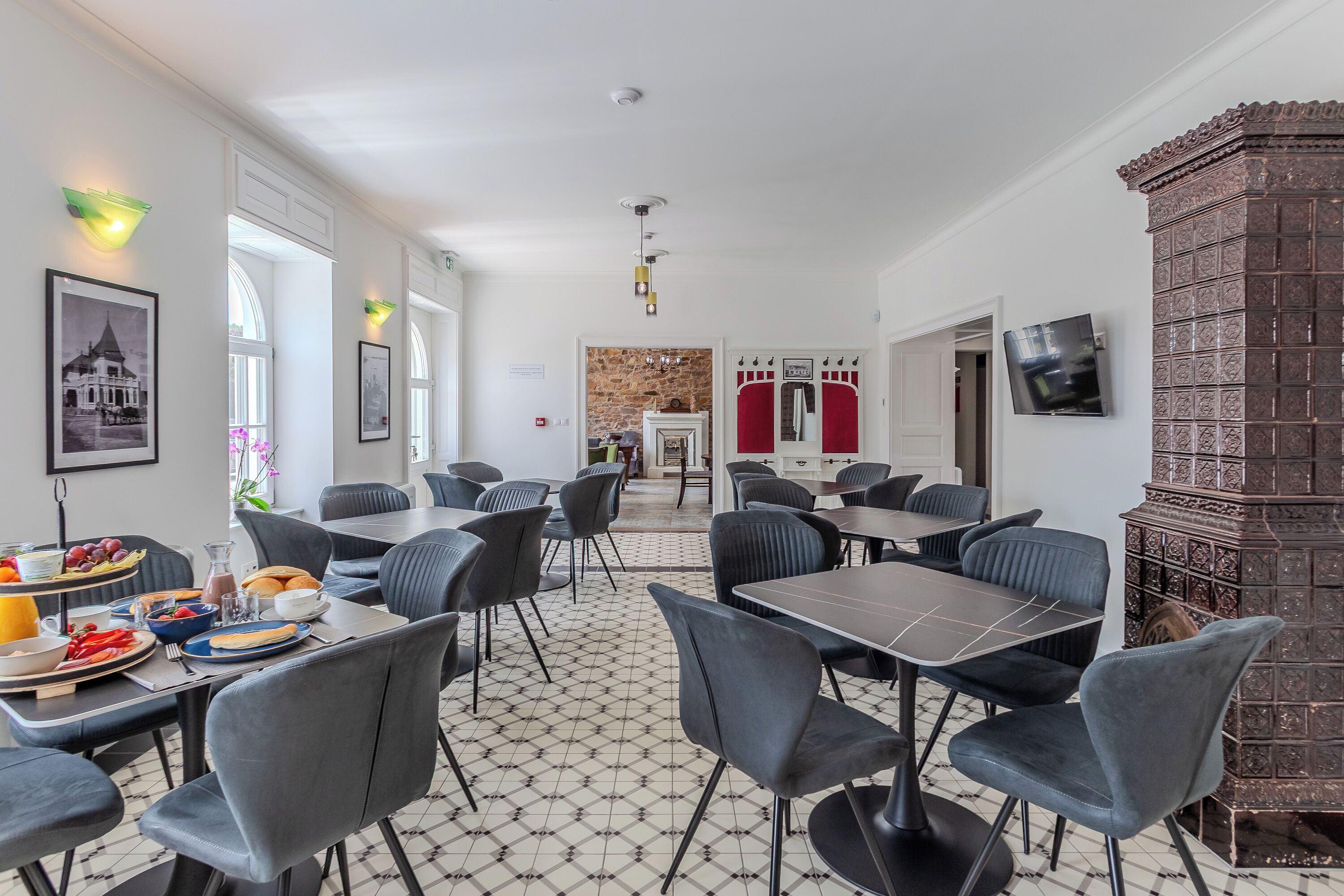 Un espace repas avec des tables et des chaises, un sol carrelé et un mur en briques.