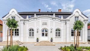 Un edificio blanco con una entrada central, ventanas arqueadas y un letrero sobre la puerta.