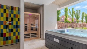 A bathroom with a colorful tiled shower, a glass-enclosed sauna, and a hot tub.