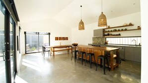 A modern kitchen with a central island, pendant lights, and a view to the outside.