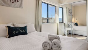 A hotel room with a large bed, a mirror, and a view of the outside. - Avalon: a striking five-bedroom, three-bathroom holiday rental. (Jindabyne)