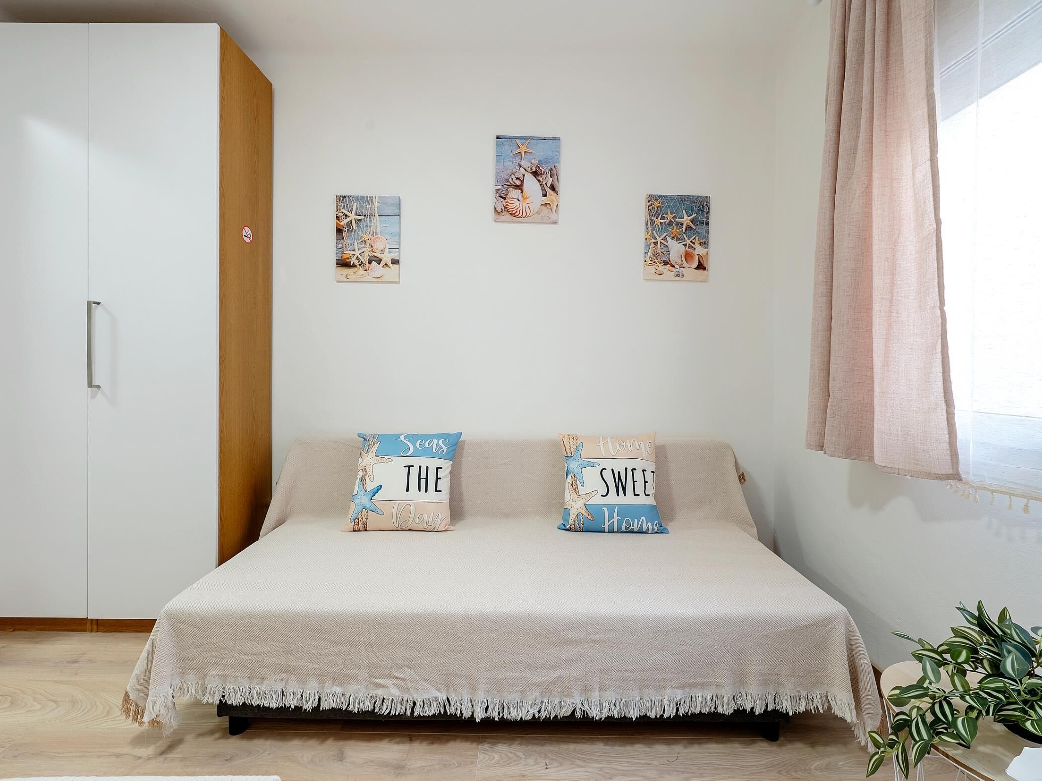 A bedroom with a bed, two pillows, a wardrobe, and wall art.