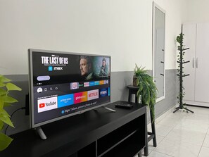 Un téléviseur à écran plat, posé sur un support noir, diffuse un film, et divers logos de services de diffusion en continu apparaissent en dessous.