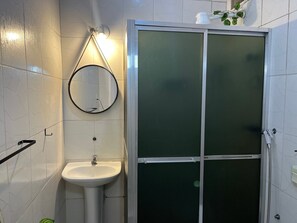 Een badkamer met een wit wastafel, een ronde spiegel en een douche met glazen wanden.