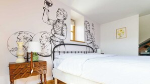 A bedroom with a bed, a wooden nightstand, a lamp, and wall art. - Logis Marie (flavigny sur Ozerain)