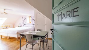 A bedroom with a bed, a table with chairs, and a green door labeled "MARIE". - Logis Marie (flavigny sur Ozerain)