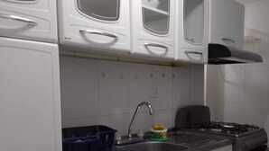 A kitchen with white cabinets, a stainless steel sink, a stove, and a refrigerator. - 2 bedroom apartment - Manga Cartagena Colombia (Cartagena de Indias)