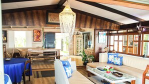 A spacious living area with a dining table, sofa, and a chandelier.