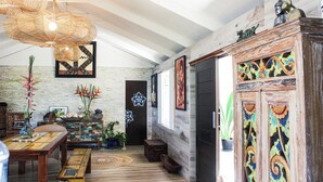 A spacious room with a high ceiling, a wooden dining table, a bench, and a decorative cabinet.