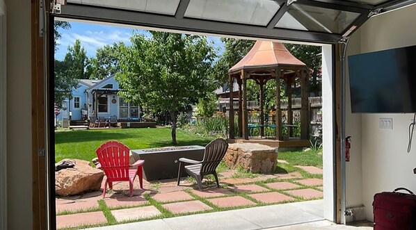 A patio with a grill, a gazebo, and a house in the background.