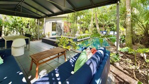 A covered outdoor seating area with a pool, surrounded by lush greenery. - Award Winning Home! BBQ-Heated Pool-2 miles from beach (Fort Lauderdale)