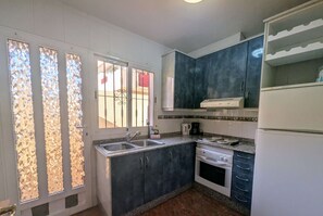 A kitchen with a sink, stove, and cabinets.