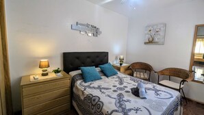 A bedroom with a bed, nightstands, a chair, a ceiling fan, and a wall-mounted light fixture. - La Zenia Ground-Floor Apt w/ Pool LZ12 (Orihuela)