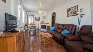 A living room with a brown leather sofa, a wooden coffee table, a television, and a fireplace. - La Zenia Ground-Floor Apt w/ Pool LZ12 (Orihuela)
