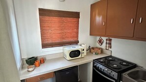 Una cocina compacta con microondas, estufa y lavamanos.