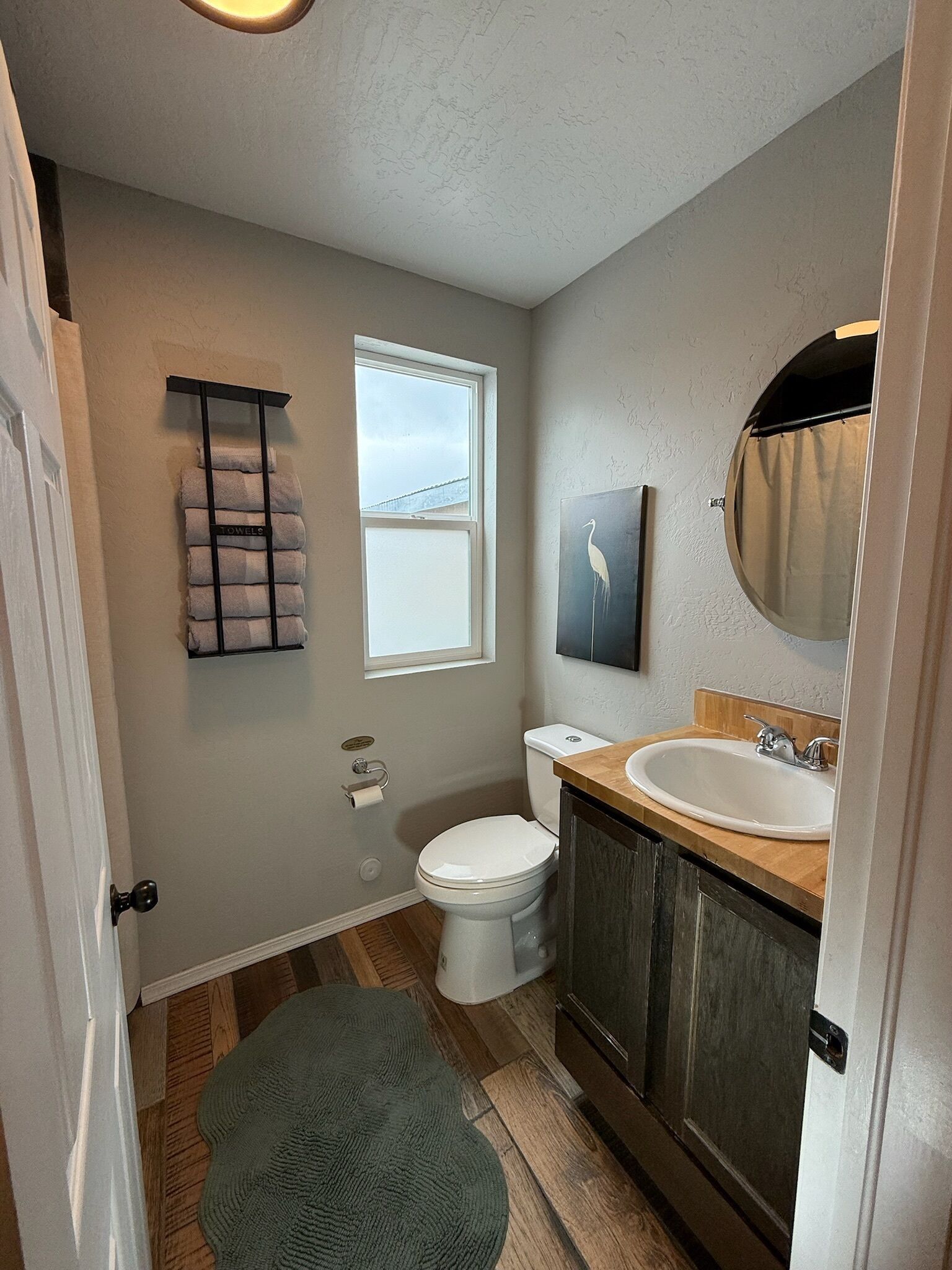A bathroom with a toilet, sink, towel rack, and a window.