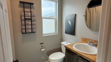 A bathroom with a toilet, sink, towel rack, and a window.