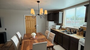 Una cocina moderna con una mesa de comedor de madera, sillas blancas y una araña.